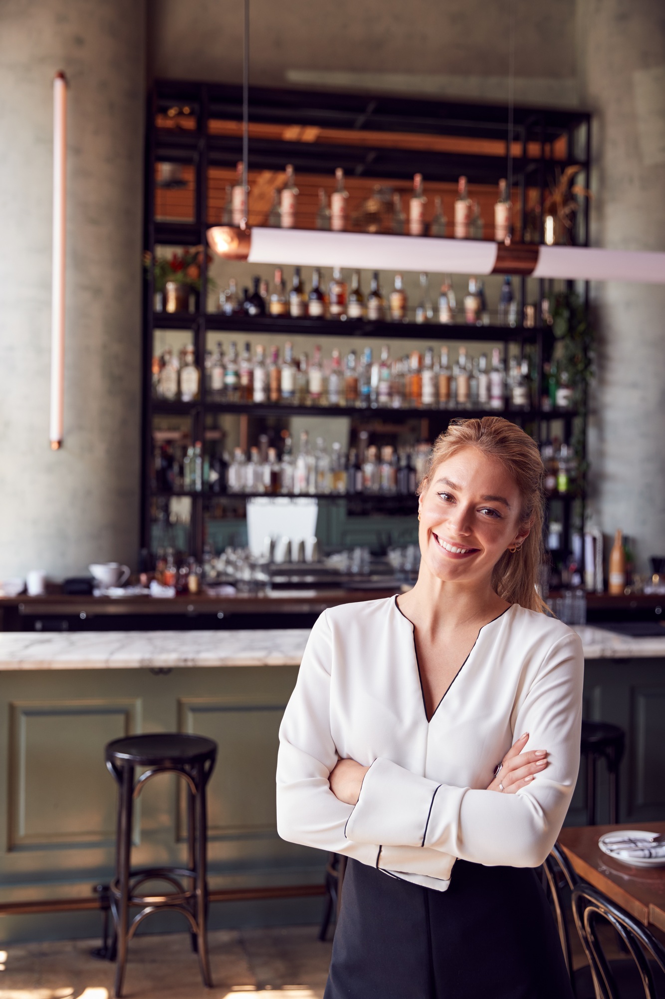 Portrait Of Confident Female Owner Of Restaurant Bar Standing By Counter