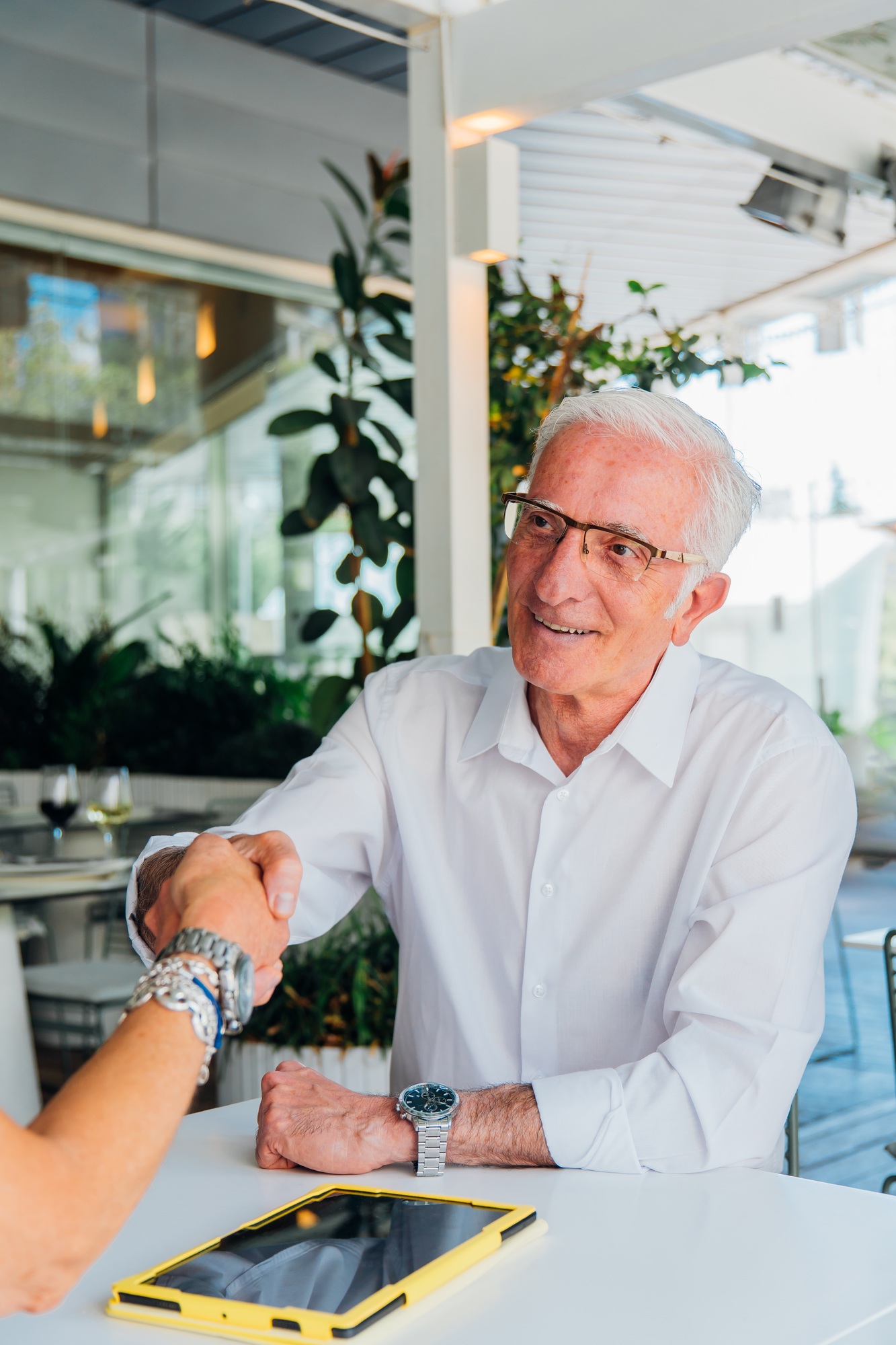 Senior businessman shaking hands with a colleague at a restaurant table