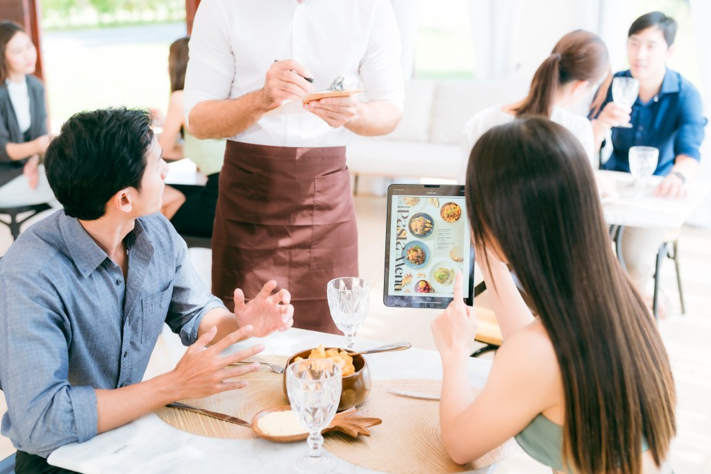 Laptop screen showing AI-driven restaurant analytics dashboard with graphs and charts.